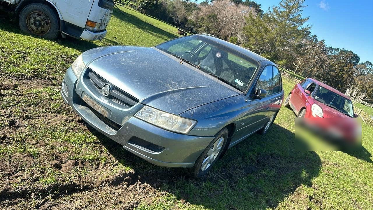 Holden Commodore parked on a front lawn awaiting free removal in Auckland