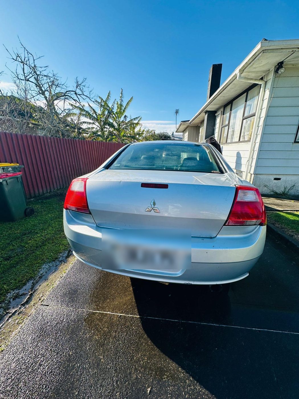 Silver Mitsubishi sedan parked in an Auckland driveway ready for cash-for-cars pickup