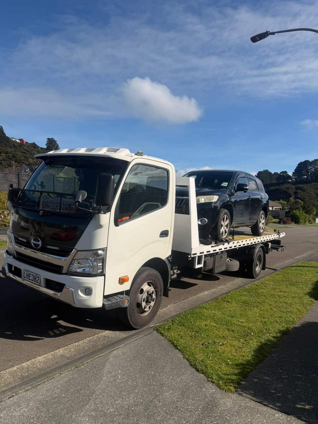 SUV loaded on a Hino flatbed tow truck for cash-for-cars removal in Auckland